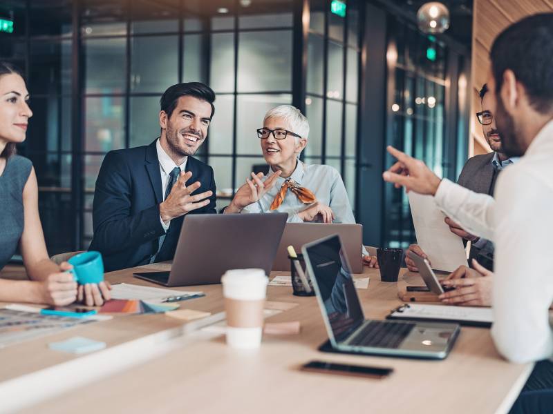 5 people sitting and discussing business in a meeting together